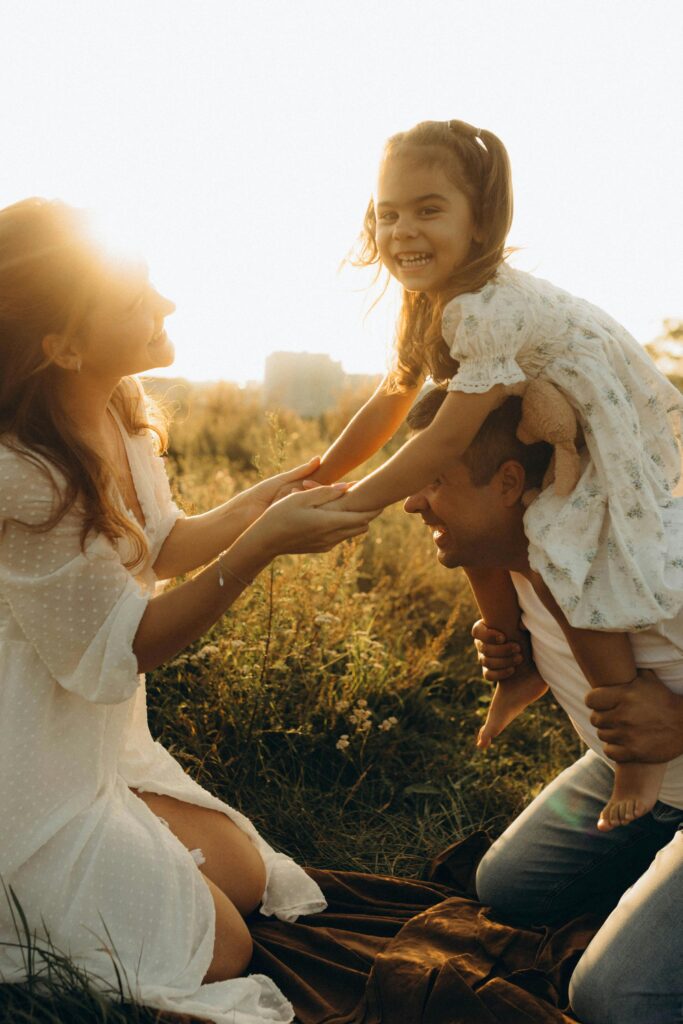 A joyful family enjoying a playful moment in a sunny field.